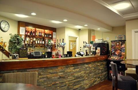 a bar in a restaurant with a clock on the wall at Orchid 3 in Ferndown
