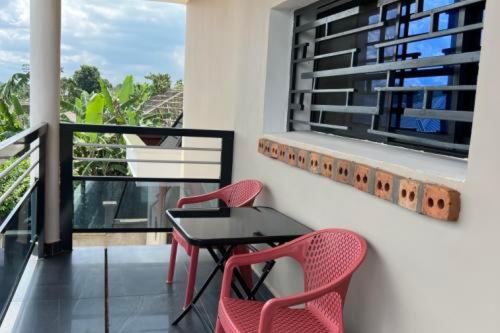a balcony with two red chairs and a black table at Résidences LELYSSE in Méyo