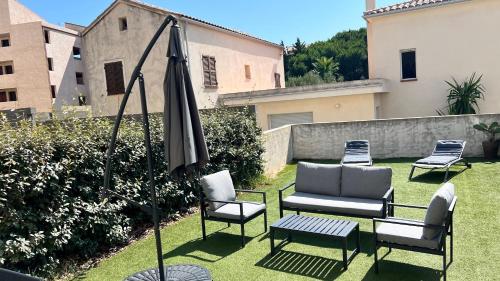 eine Terrasse mit Stühlen, Sonnenschirm und Tisch in der Unterkunft Appartement T2 - Rez-de-Jardin, proche plage et commerces in Calvi