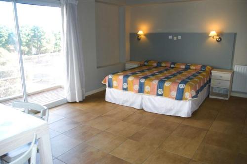 a bedroom with a bed and a large window at Bagu Ayres de Mar Apart in Pinamar