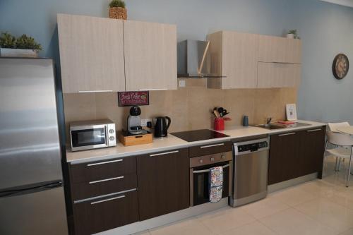 a kitchen with brown cabinets and a sink and a microwave at Maltese Coastal Escape in Sliema