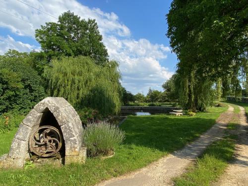 a stone oven in the grass next to a pond at Gîte d'exception - Manoir de Sacquenay in Sacquenay