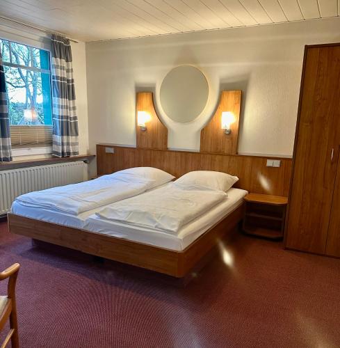 a bedroom with a bed with a mirror on the wall at Landgasthof "Zum grünen Walde" in Nordholz