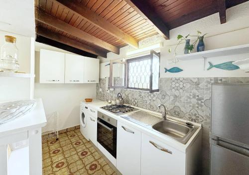 Biała kuchnia ze zlewem i kuchenką w obiekcie Solemar Sicilia - Seaside House Capo Zafferano w mieście Santa Flavia