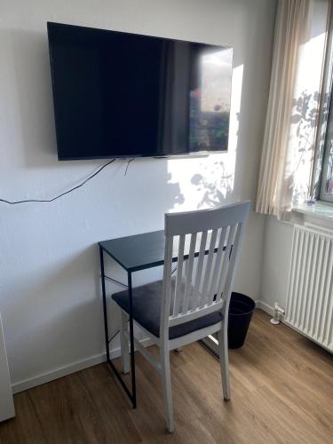 a table with a chair and a television on a wall at Hos Heidi in Fredericia