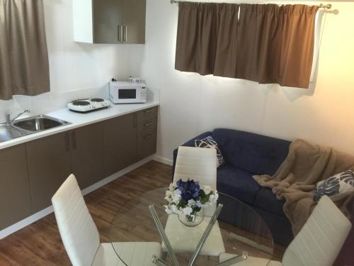 a living room with a blue couch and a kitchen at Oakridge Motel Tourist Park in Oakey