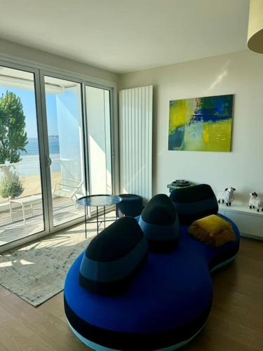 - un salon avec une table et un fauteuil pour poufs bleus dans l'établissement Les Mouettes Face Mer La baule, à La Baule