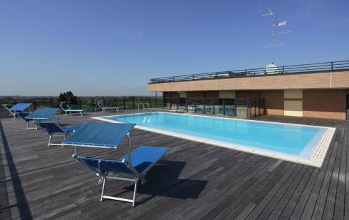 a swimming pool with chairs and a building at Grand Hotel Forlì in Forlì