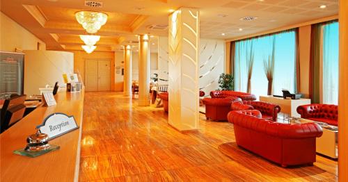 a lobby with red leather chairs and a reception desk at Grand Hotel Forlì in Forlì