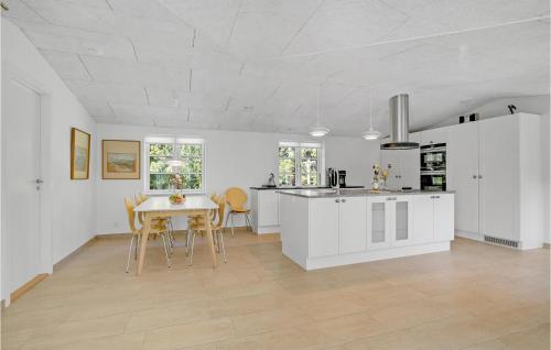 a kitchen with white cabinets and a table and chairs at 4 Bedroom Amazing Home In Hurup Thy in Sønder Ydby