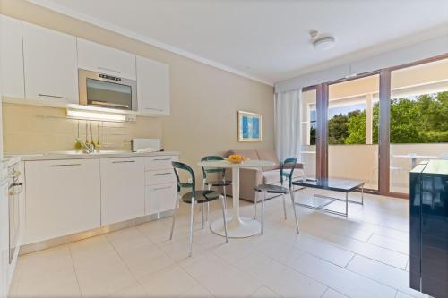 a kitchen and dining room with a table and chairs at The Residence Aparthotel in Podstrana