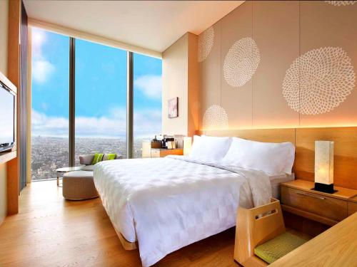 a bedroom with a large bed and large windows at Osaka Marriott Miyako Hotel in Osaka