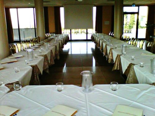 a row of tables in a room with white table cloths at Grand Hotel Forlì in Forlì