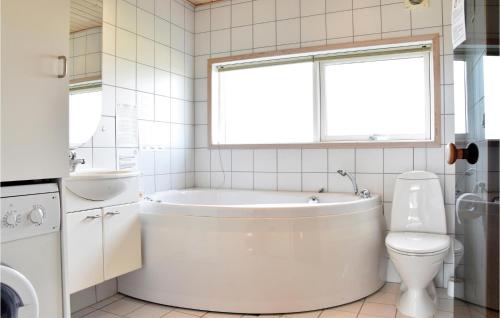 un bagno bianco con vasca e WC di Søndervig Ferieby a Nørby