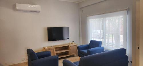 a living room with blue chairs and a flat screen tv at Tigre Centro Cochera Gratis in Tigre
