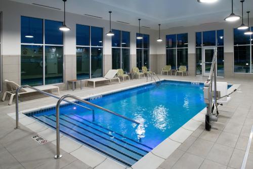 a swimming pool in a building with tables and chairs at Element Kansas City Overland Park in Leawood