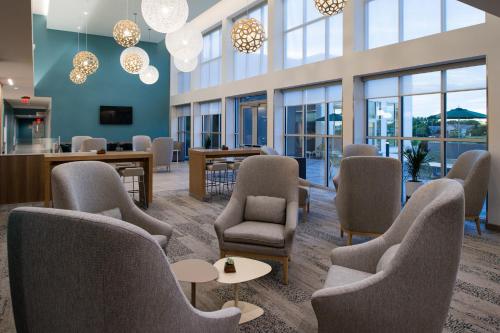 a waiting room with chairs and tables and windows at Element Kansas City Overland Park in Leawood