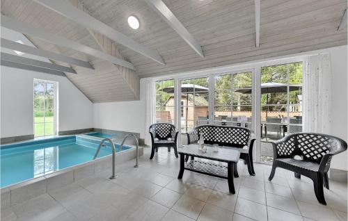 a swimming pool in a room with chairs and a table at Gorgeous Home In Ulfborg With Kitchen in Ulfborg