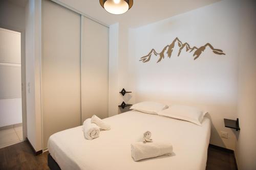 une chambre avec un lit blanc avec des serviettes dessus dans l'établissement Le Majuscule, à Annecy