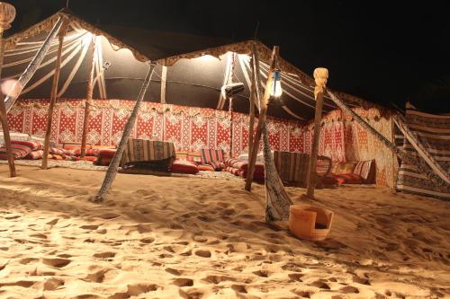 a tent with chairs in the sand at night at Bedouin Oasis Desert Camp- Ras Al Khaimah in Ras al Khaimah