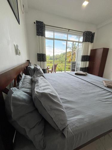 a large bed in a bedroom with a large window at Paddy Field Paradise by Sri Villa Rest in Hikkaduwa