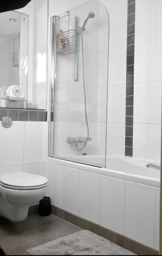 a white bathroom with a shower and a toilet at LUX 2bed City Centre and AO Arena Free Parking Modern Apt in Manchester
