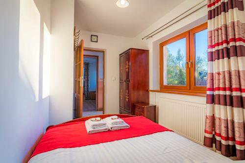 a bedroom with a red bed with towels on it at Górski Pałacyk Kompleks obiektów in Kościelisko