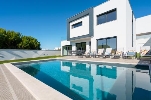 a white house with a swimming pool in front of it at Villa Beach and Friends with ocean view in Lourinhã