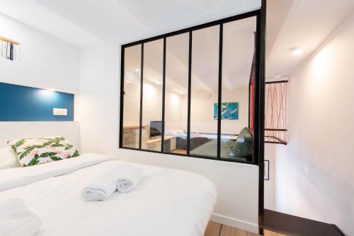 sypialnia z białym łóżkiem i dużym oknem w obiekcie LE CHANCEUX fabuleux duplex en design, pour loisir en couple ou congrès w Cannes