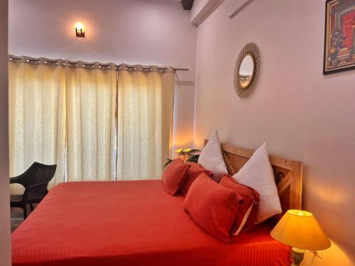 a bedroom with a bed with red sheets and pillows at Vasantvasoj Homestay in Pauri