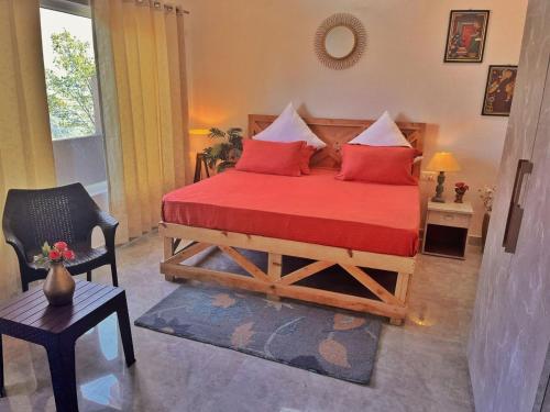 a bedroom with a bed with red pillows and a chair at Vasantvasoj Homestay in Pauri