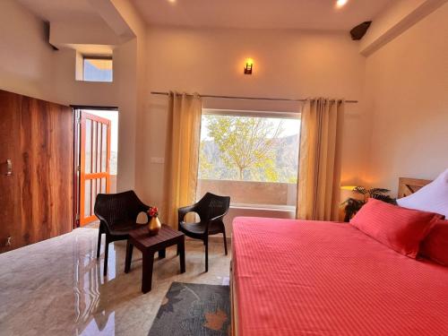 a bedroom with a bed and chairs and a window at Vasantvasoj Homestay in Pauri