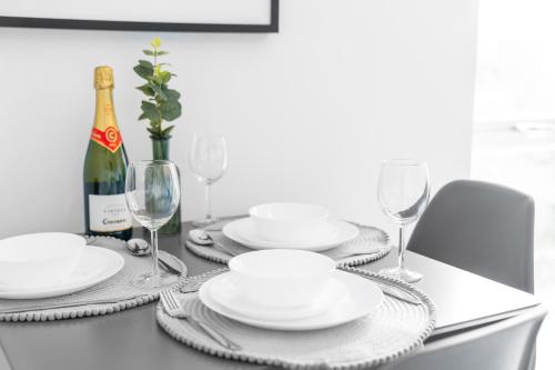 a table with white plates and a bottle of wine at Two Bedroom Apartment - Parking - Sleeps 3 - Fast WiFi - Netflix - Top Rated - 27BC in Sleightholme