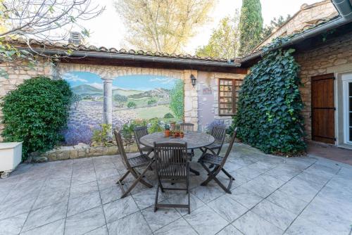 a patio with a table and chairs and a wall with a mural at Le Patio in Velleron