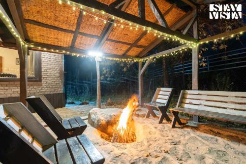 a fire pit in a patio with benches and lights at StayVista at Crystal Creek 2BR villa in Gulmarg with Free Breakfast in Gulmarg