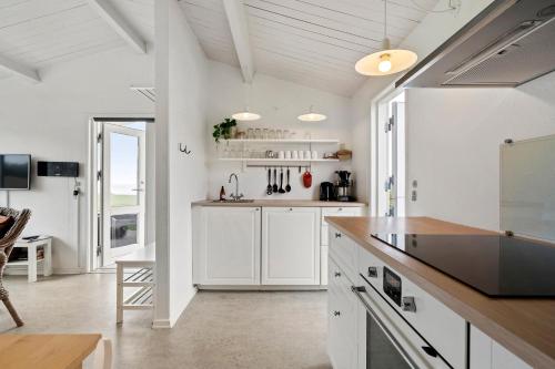 a kitchen with white cabinets and a counter top at Cozy Coastal Retreat on the beach in Brenderup