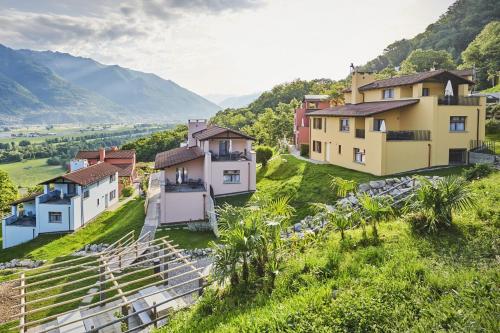 a group of houses on a hill with mountains in the background at Reka-Ferienanlage Magadino in Magadino