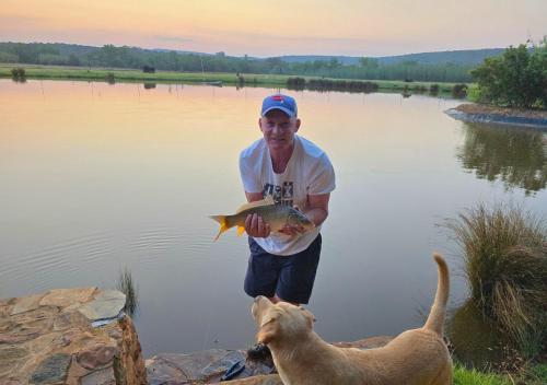 a man holding a fish and a dog in the water at Imbabali Retreat & Venue in Magaliesburg