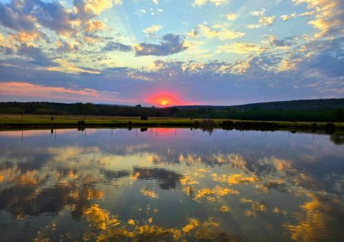 a reflection of the sunset in a lake at Imbabali Retreat & Venue in Magaliesburg