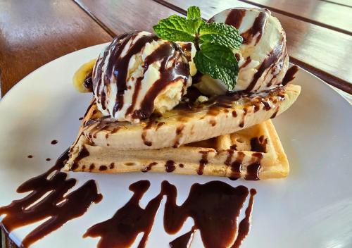 a plate of waffles with ice cream and chocolate sauce at Imbabali Retreat & Venue in Magaliesburg