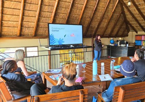 a group of people sitting around a table watching a presentation at Imbabali Retreat & Venue in Magaliesburg