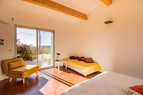 ein Schlafzimmer mit einem Bett, einem Stuhl und einem Fenster in der Unterkunft Maison Aux Vents in Monacia-dʼAullène