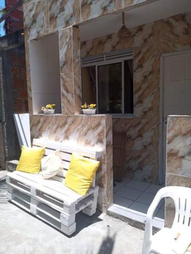 a white bench with two yellow pillows on a patio at Casa Amarela, Ilha dos Frades in Salvador