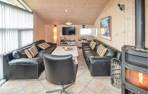 a living room with leather couches and a fireplace at Holiday Home Alexandravej Løkken Xi in Løkken