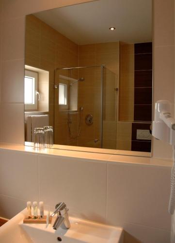 a bathroom with a sink and a large mirror at Brauereigasthof Püttner in Schlammersdorf