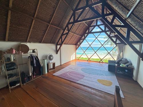 a large room with a large window and a wooden floor at Valhalla Mentawai in Katiet