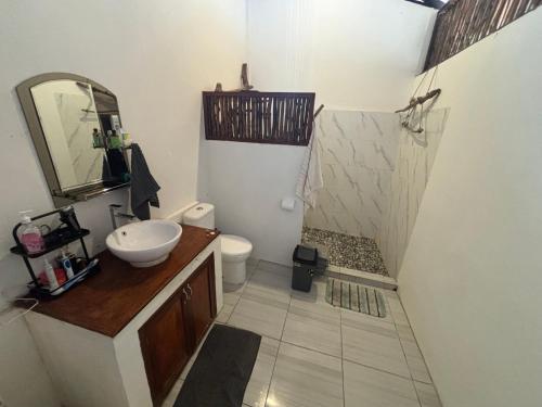 a bathroom with a sink and a toilet and a mirror at Valhalla Mentawai in Katiet