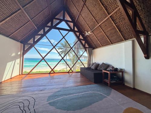 a living room with a couch and a large window at Valhalla Mentawai in Katiet