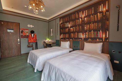 two beds in a hotel room with a woman standing in the background at 星澄風旅 Zela Design Hotel in Kaohsiung