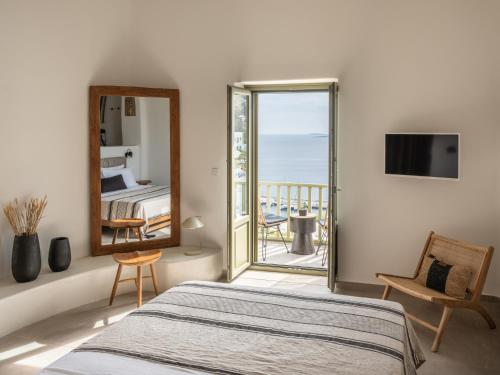 a bedroom with a bed and a mirror and a balcony at Saluti Da Stampalia Chora in Pera Gyalos